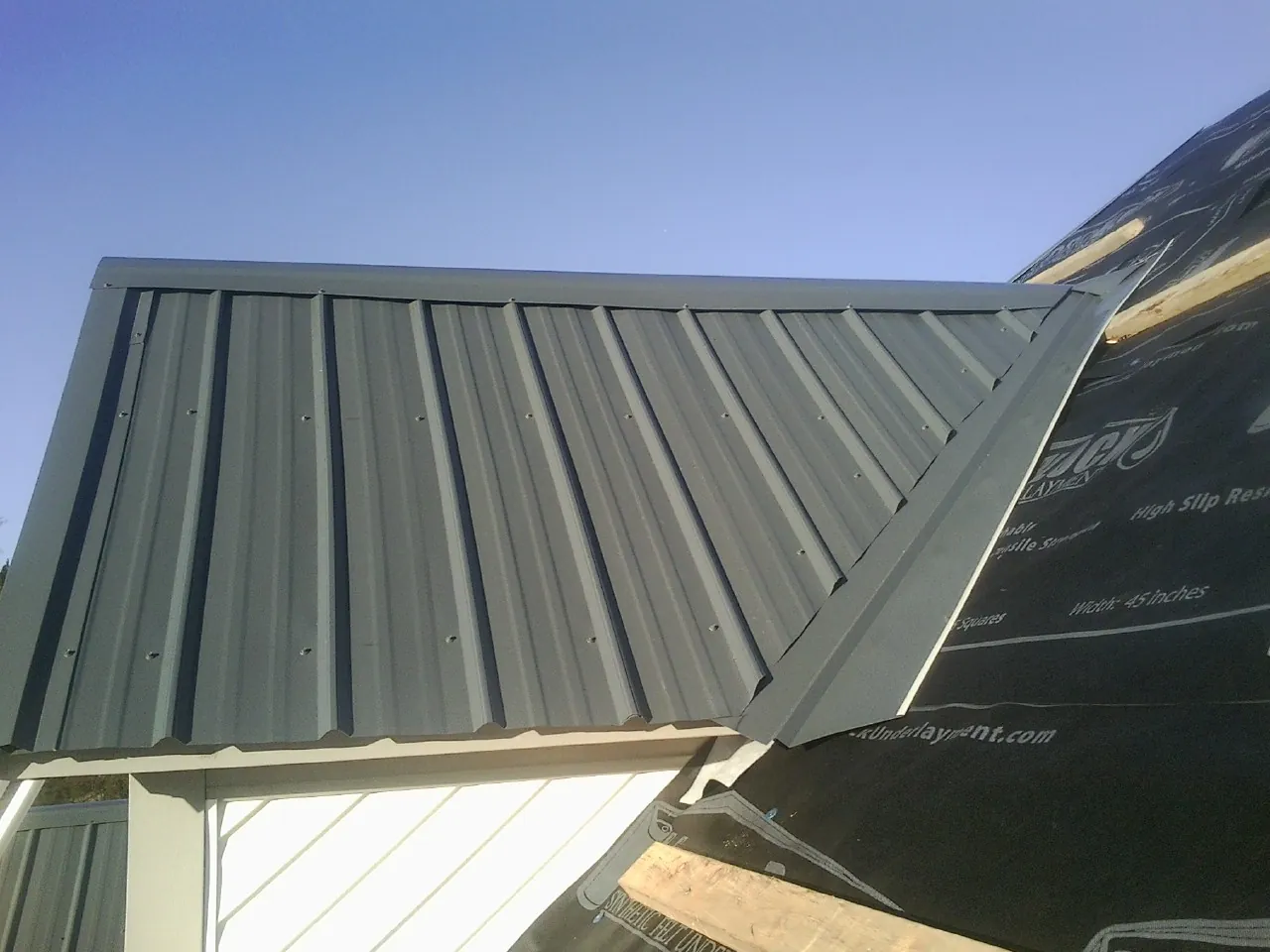 Gray metal roof panels going on over a garage gable in Grant Park