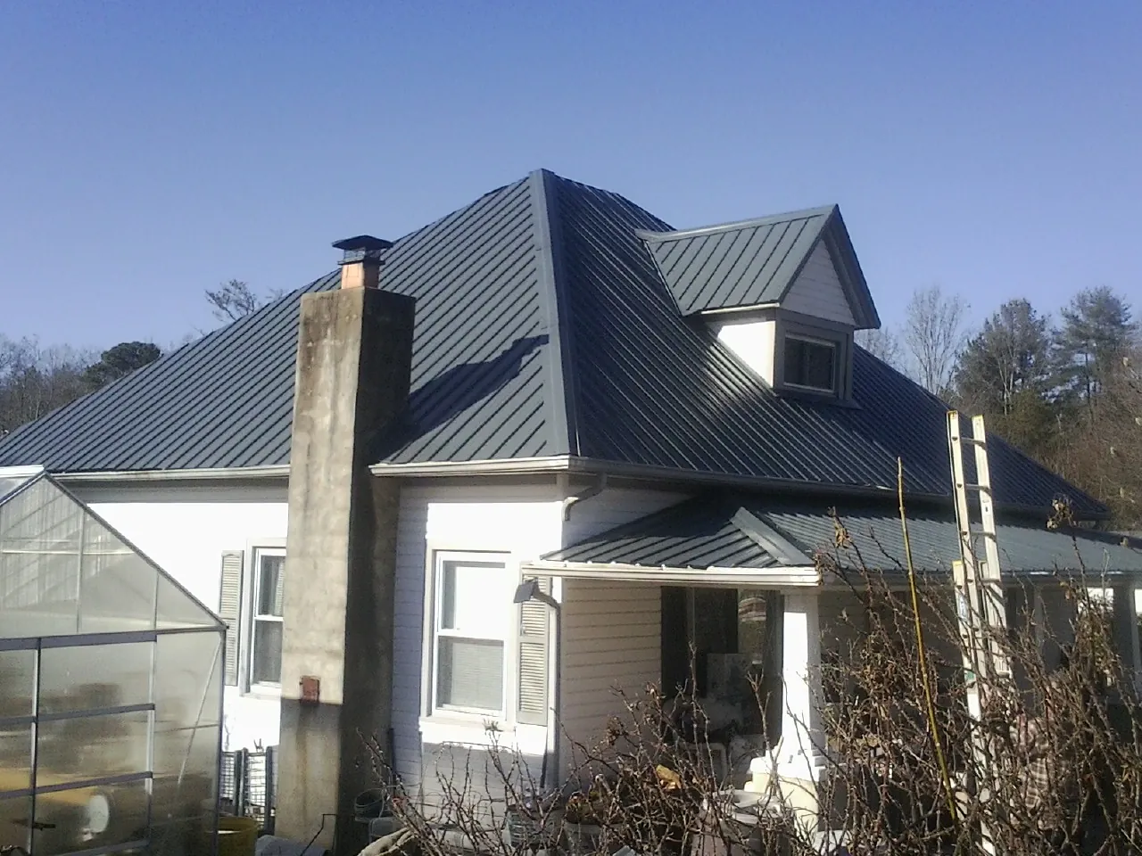 Dark blue standing seam metal roof on a white farmhouse with dormer — Slate & Tile Roof Repair by Roofing Brothers in Grant Park