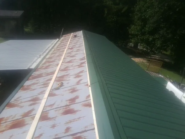 Old rusted panels beside newly installed green metal roofing — Wind Damage Roof Repair by Roofing Brothers in Grant Park
