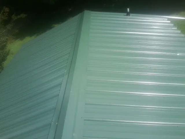 New green metal panels meeting at the ridge of a roof — Flat Roof Repair work by our crew in Grant Park