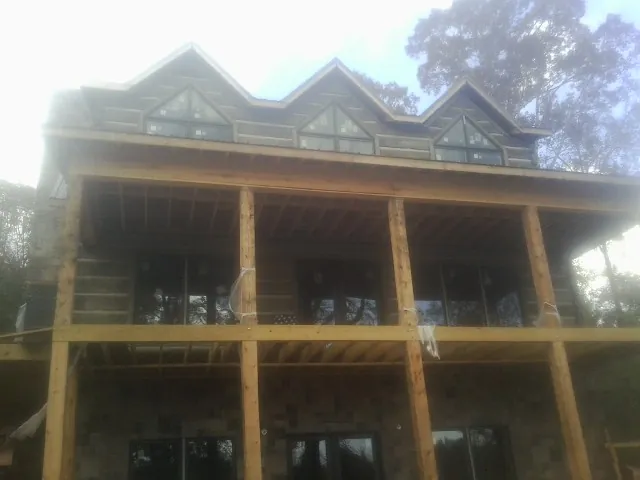 Dormers and porch framing on a large log home under construction — Roof Coating work by our crew in Grant Park