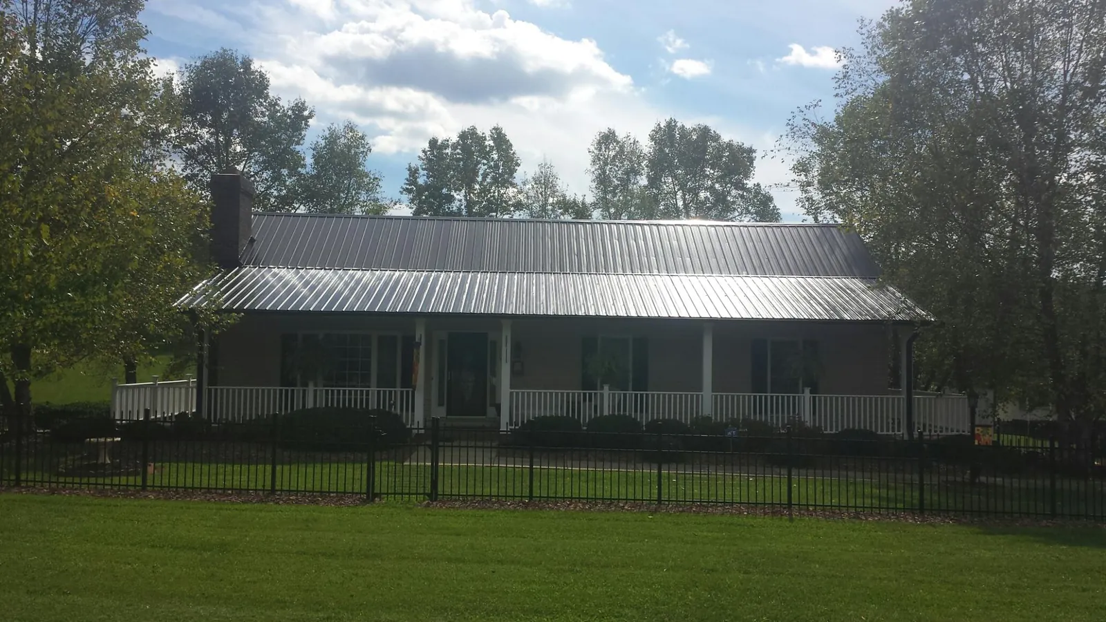 Gray metal roof on a brick ranch with a full width front porch — Gutter Guard Installation work by our crew in Grant Park