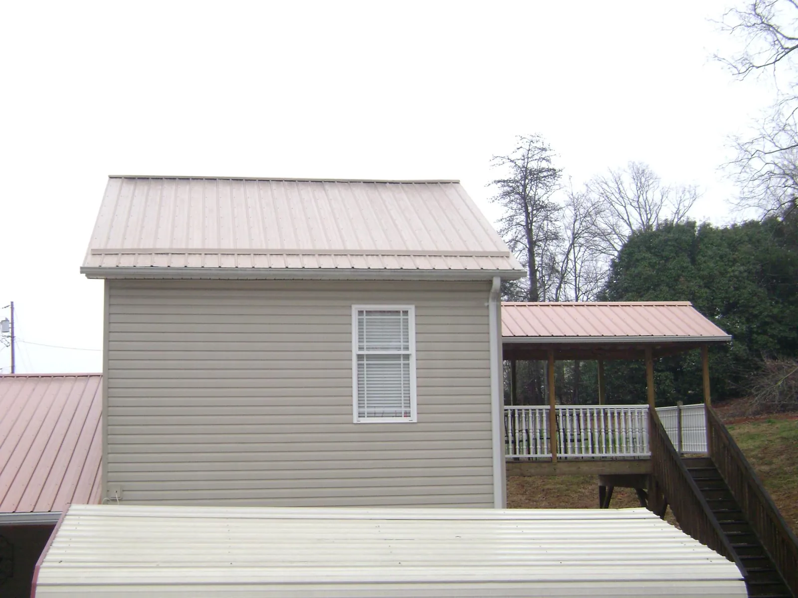 Tan metal roofs on a two story addition and attached porch, from a Roof Replacement job in Grant Park