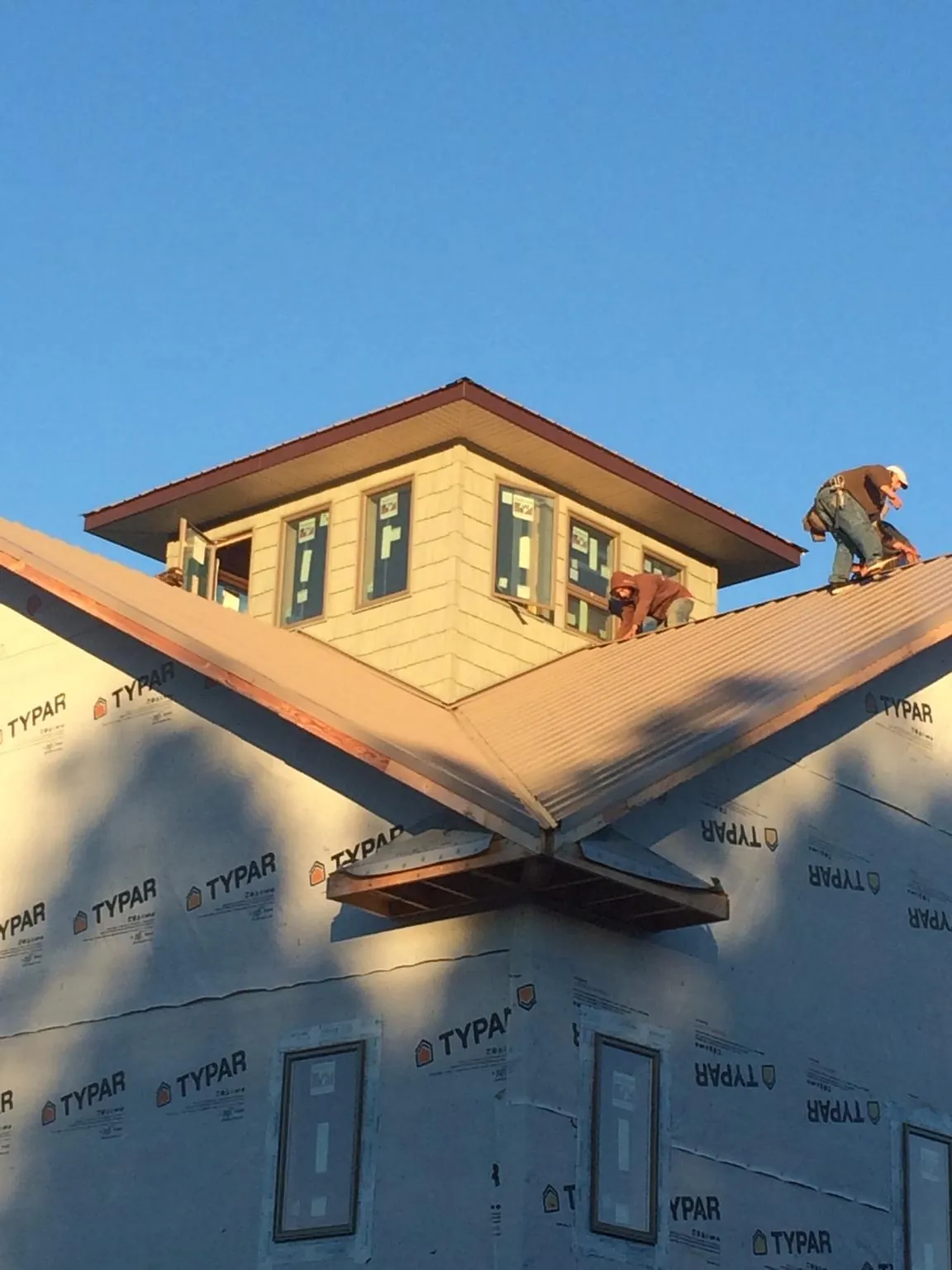 Roofers working around a rooftop cupola on a new metal roof at sunset — Roof Waterproofing in Grant Park by Roofing Brothers